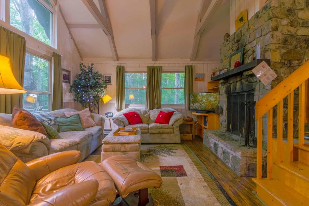 a living room with couches and a stone fireplace at Benzine Farm in Beech Mountain