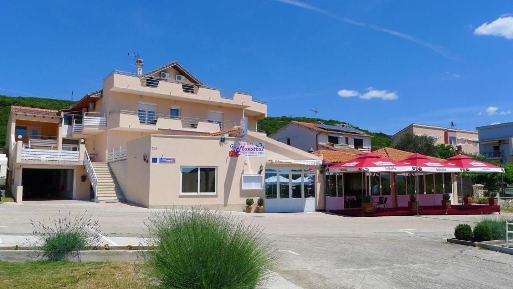 ein Gebäude mit roten Sonnenschirmen auf einem Parkplatz in der Unterkunft Apartments Maestral in Sveti Petar