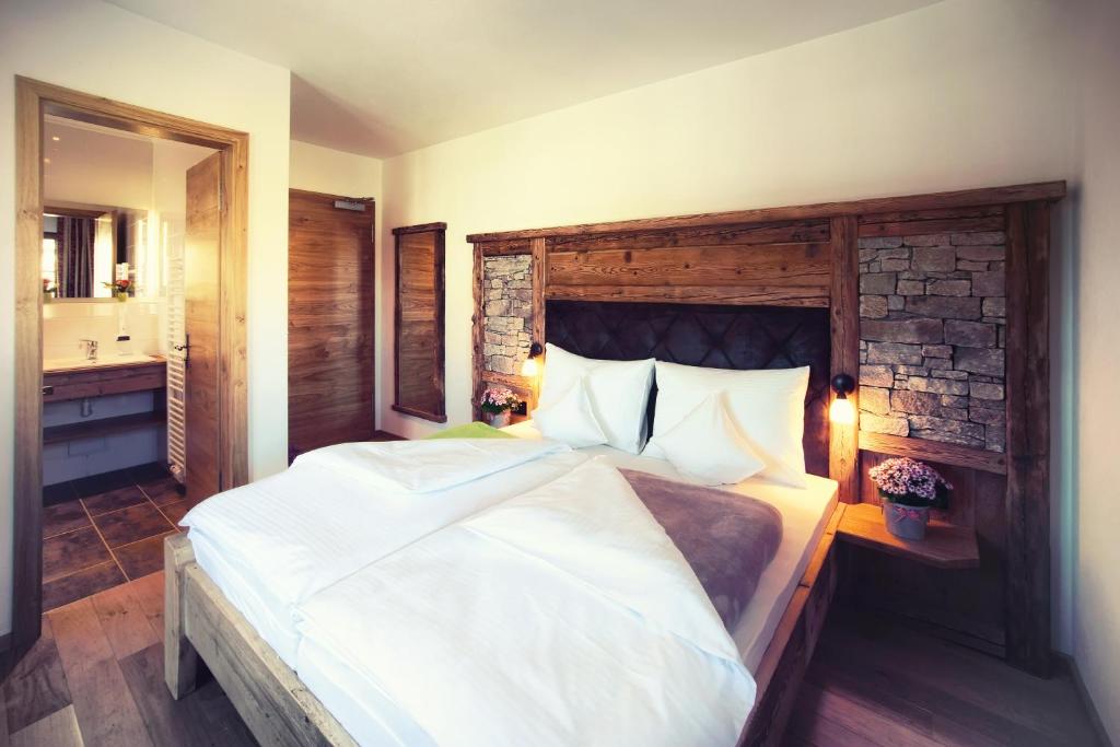 a bedroom with a large white bed and a bathroom at Gasthaus Georg Ludwig Maising in Pöcking