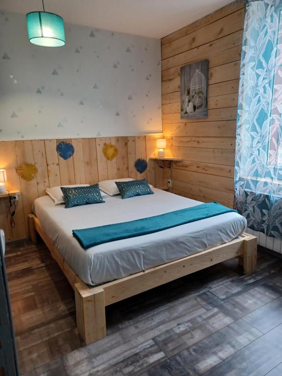 1 dormitorio con 1 cama grande y paredes de madera en Le D'HÔME en Noyers-sur-Cher