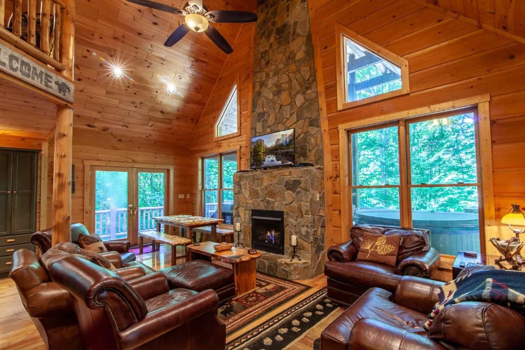 a living room with leather furniture and a stone fireplace at Chestnut Falls in Beech Mountain
