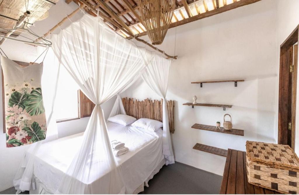 een slaapkamer met een bed met een klamboe bij Cores da Vila Caraíva - 1min do mar in Caraíva