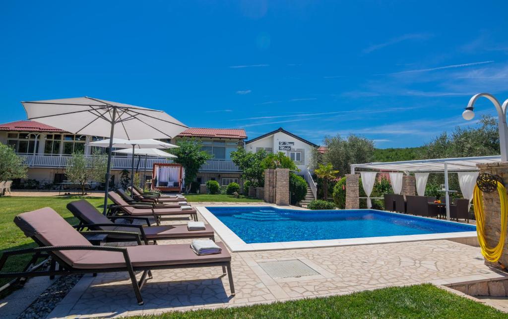 un patio trasero con piscina con sillas y sombrilla en Villa Medo en Drinovci