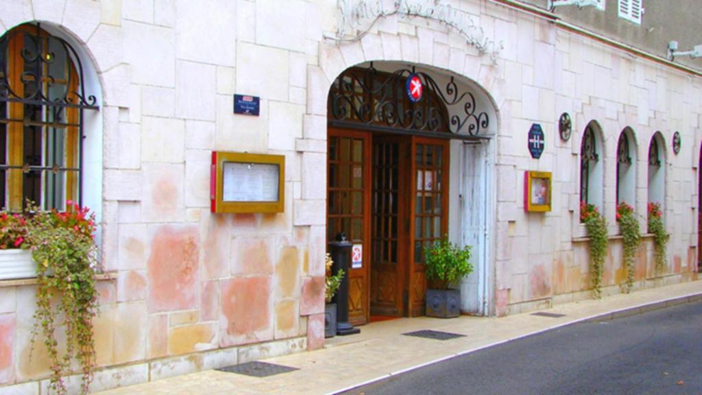 kamienny budynek z dużymi drewnianymi drzwiami na ulicy w obiekcie The Originals Boutique, Hostellerie des Trois Pigeons, Paray-le-Monial (Inter-Hotel) w mieście Paray-le-Monial