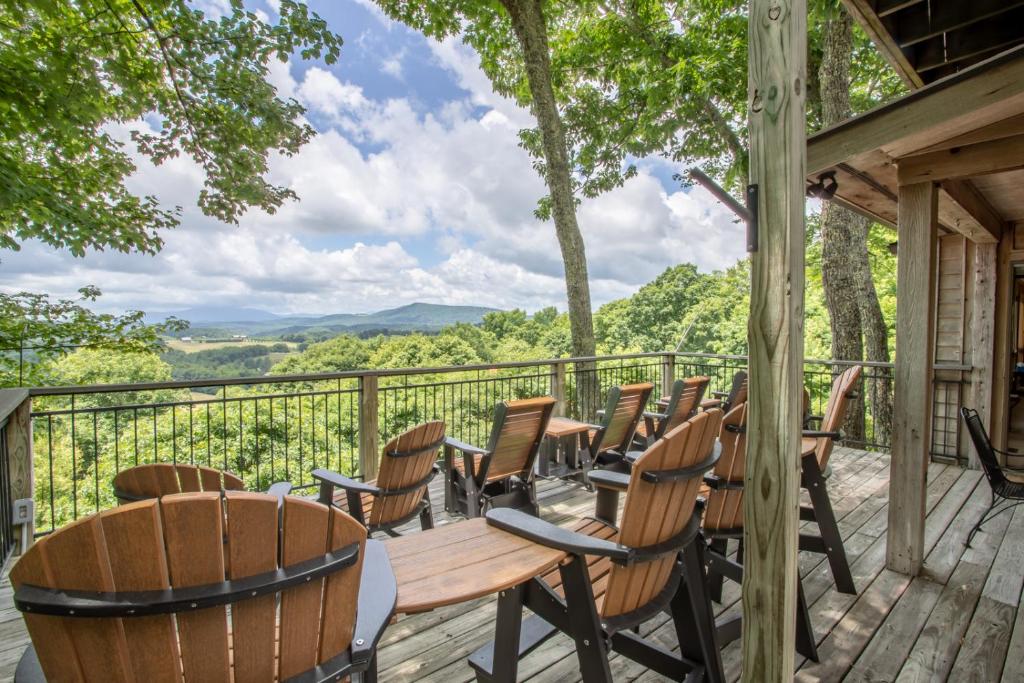 a deck with chairs and tables and a view at Serendipity in Blowing Rock