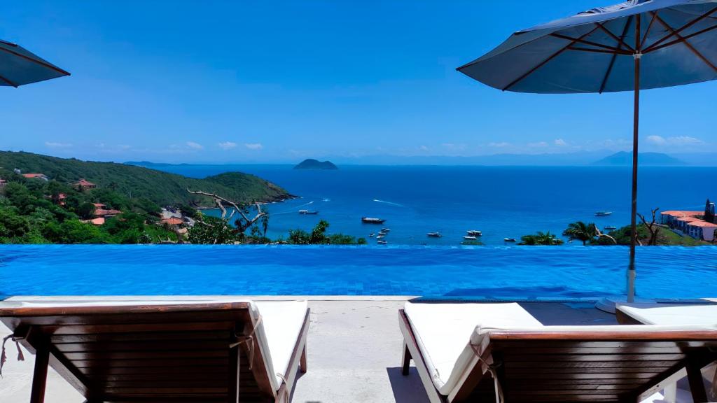 uma vista para uma piscina com cadeiras e um guarda-sol em Buzios Mar Hotel em Búzios