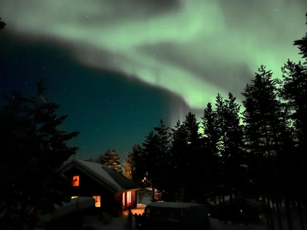 an aurora is lighting up the sky over a cabin at Revontulen Tupa in Kaamanen