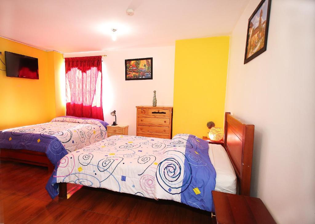 a bedroom with two beds and a dresser at Hostal Bavaria de la Alameda in Quito