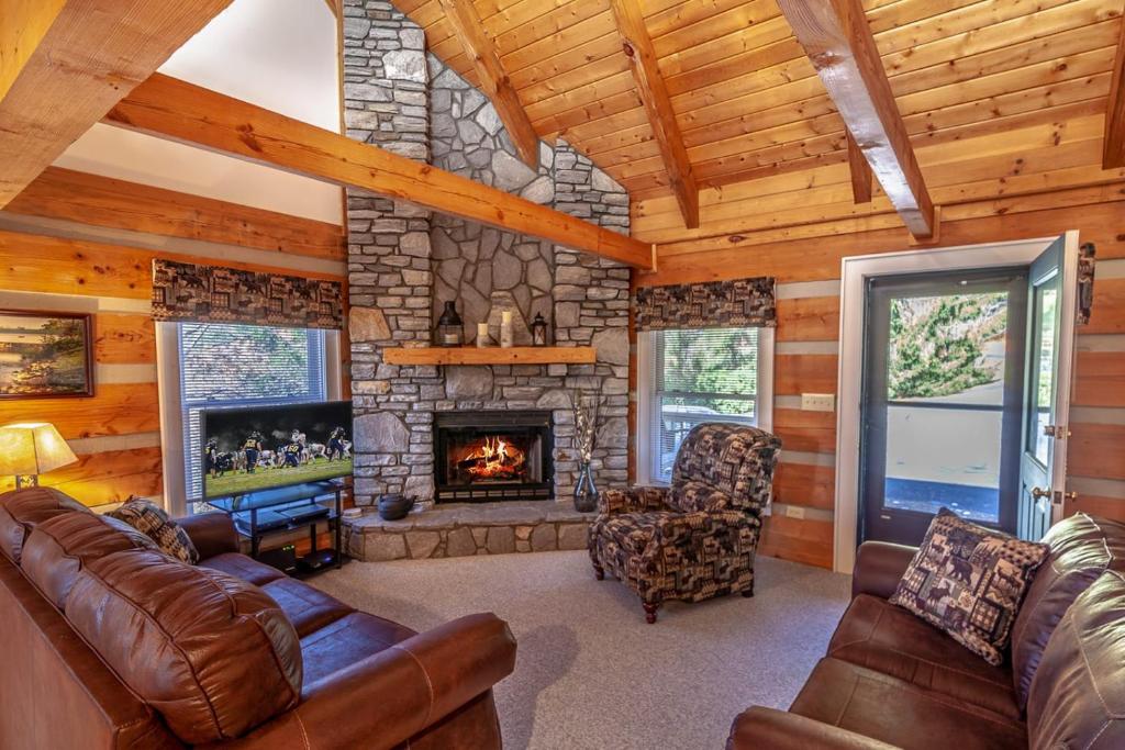 a living room with leather furniture and a stone fireplace at Sugar Shack in Banner Elk