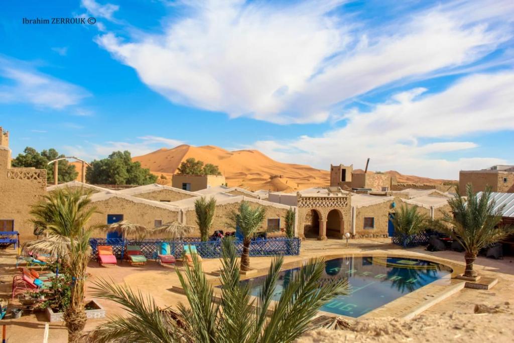 een resort met een zwembad in de woestijn bij Auberge Kasbah Merzouga in Merzouga