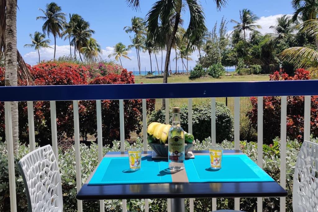 a blue table with two glasses on a balcony at Parfum des îles - vue mer, plage à 30m et piscine en option in Le Gosier