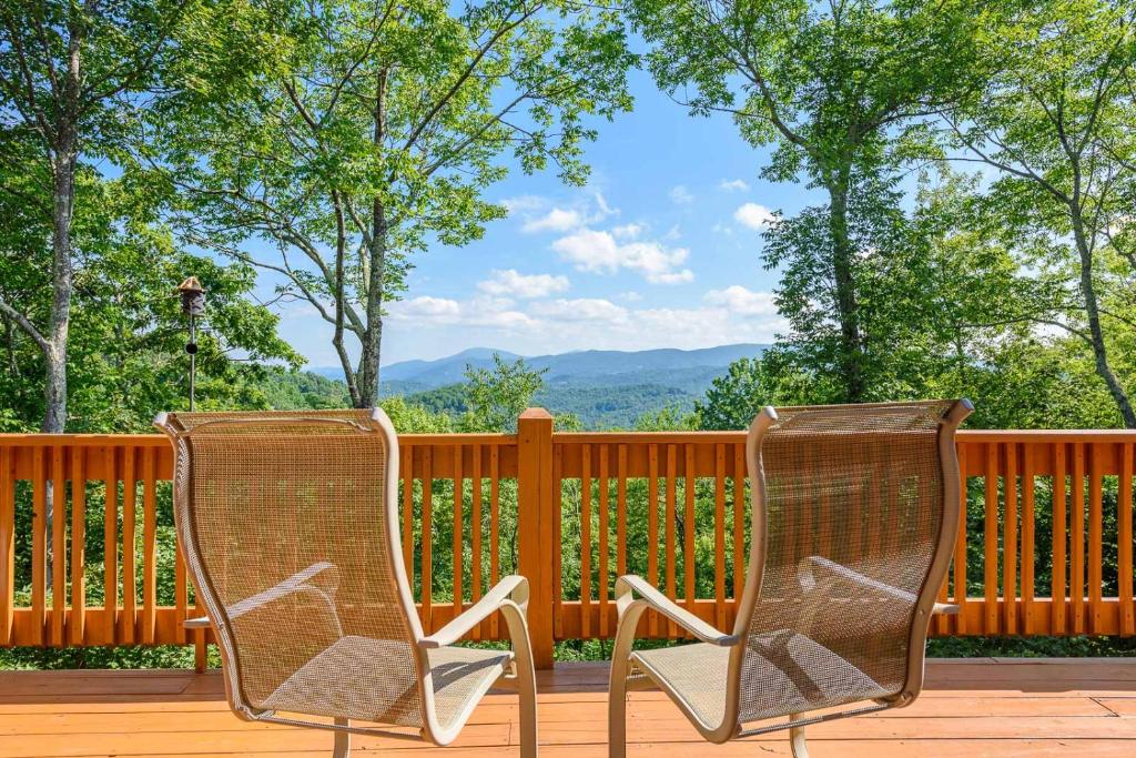 two chairs sitting on a deck with a fence at Valle Crucis Overlook in Banner Elk