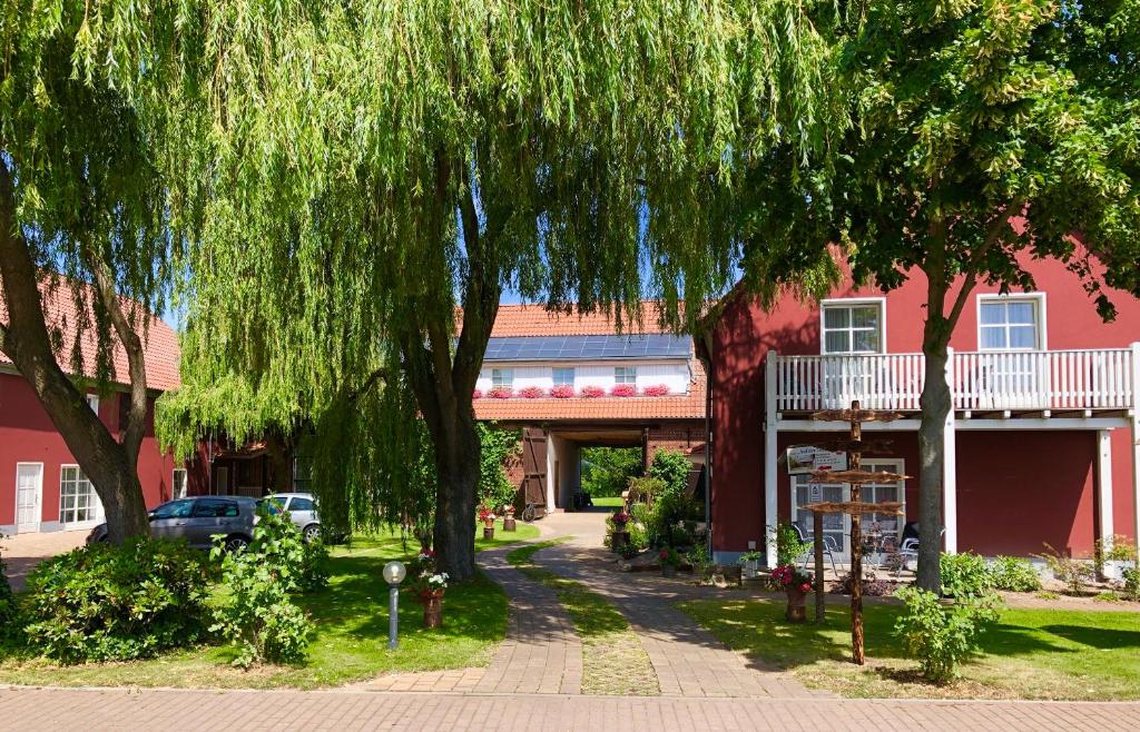 a red building with a tree in front of it at Pension Auf der Tenne in Klöden