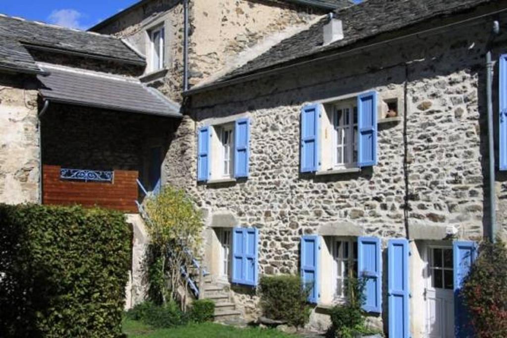 a stone house with blue shutters on it at Gîte La Parenthèse in Saint-Hostien