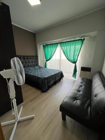 a bedroom with a bed and a couch and a fan at Naomi in Mar del Plata