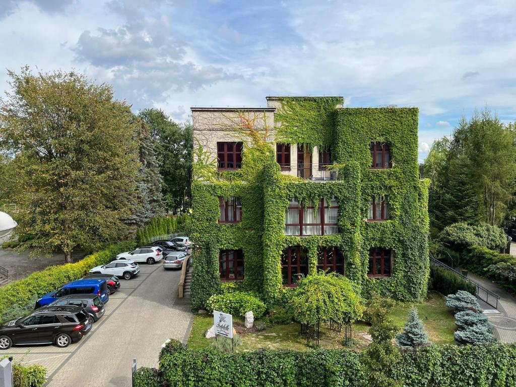 a building covered in green ivy next to a parking lot at La Bouche Appartements in Oświęcim