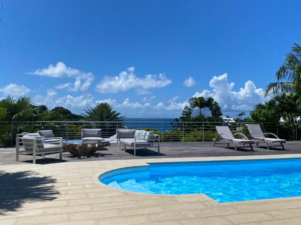a swimming pool with chairs and a view of the ocean at Villa Anse Vinaigri - Plage à pieds in Le Gosier
