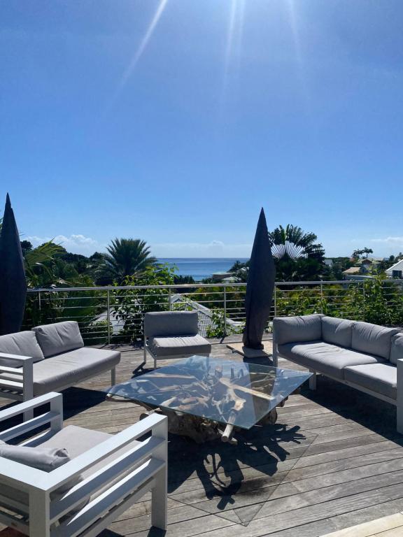 a patio with couches and a glass coffee table at Villa Anse Vinaigri - Plage à pieds in Le Gosier