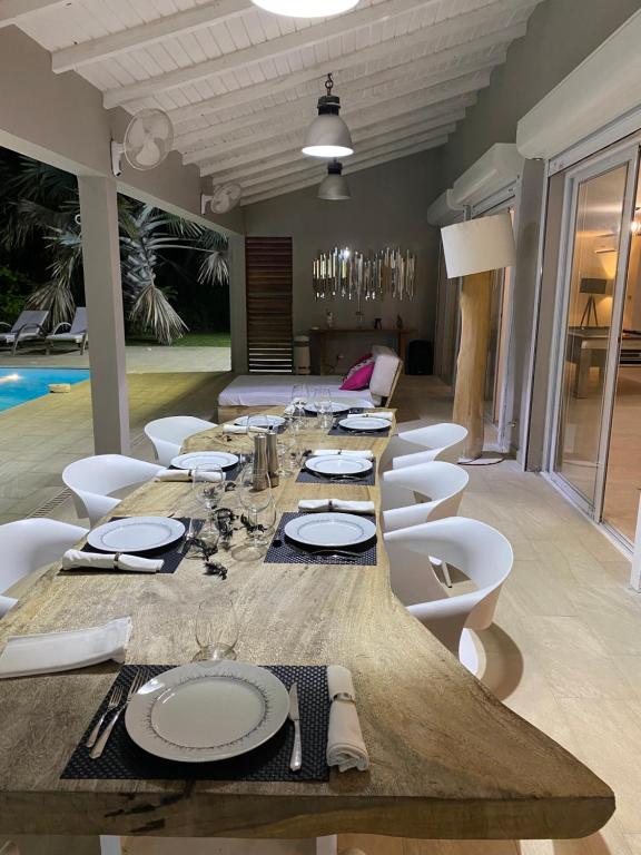 a long wooden table and white chairs in a room at Villa Anse Vinaigri - Plage à pieds in Le Gosier
