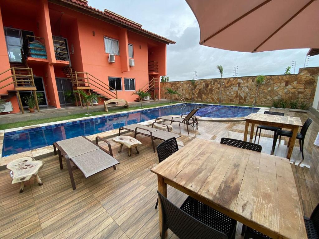 a patio with tables and chairs next to a pool at Condomínio Villamares in Luis Correia
