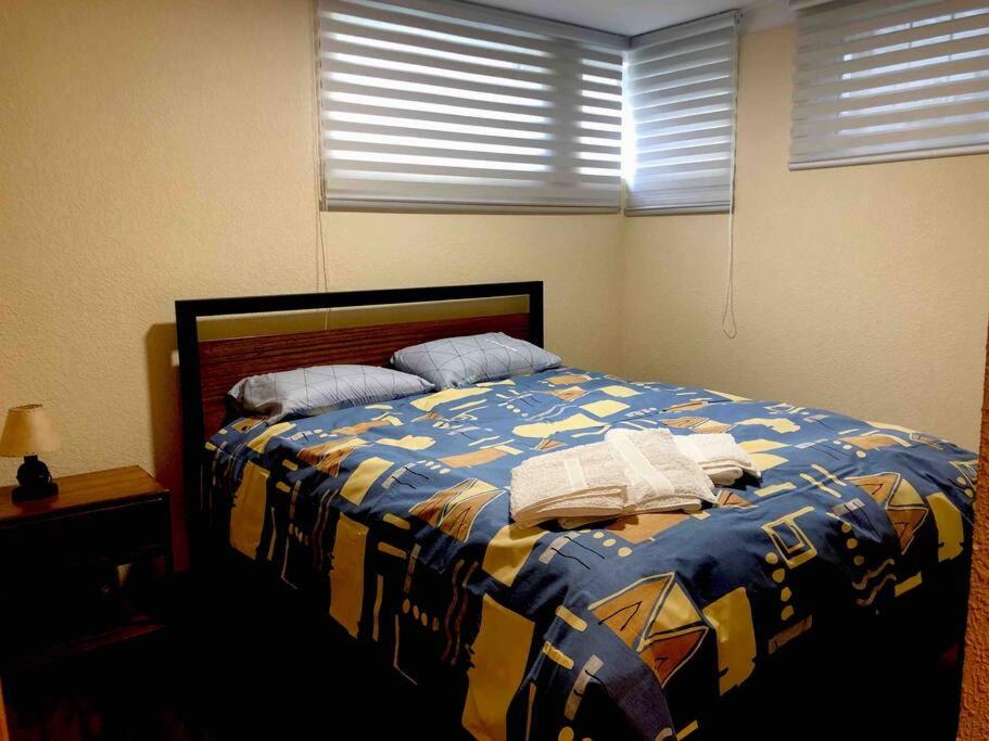 a bedroom with a bed with a blue and yellow blanket at Apartamento acogedor en Achumani in La Paz