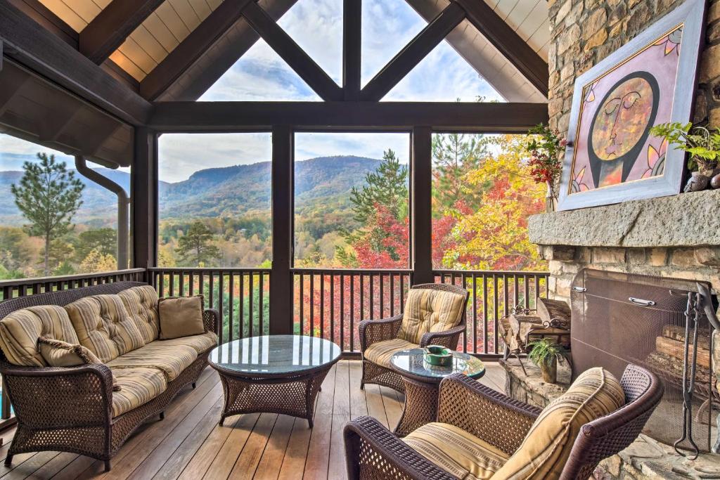 Stunning Mill Spring Home with Mountain Views! في Mill Spring: شاشة في الشرفة مع أريكة وكراسي ومدفأة