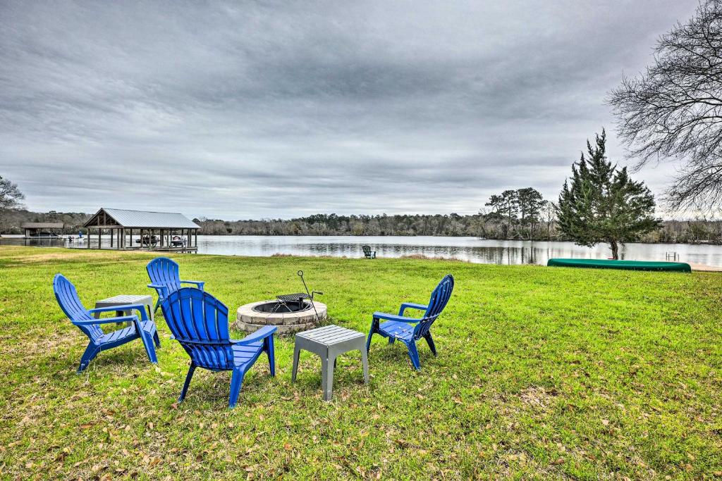 três cadeiras e uma mesa num campo ao lado de um lago em Lakefront House with Boat Dock on Lake Conroe! em Willis