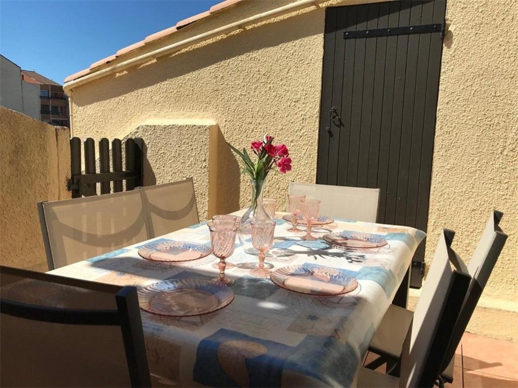 une table avec des verres et un vase de fleurs sur elle dans l'établissement Appartement T2 Mezzanine, 6 couchages, bord de plage, parking privé, proche commerces et Aqualand - FR-1-81-47, à Port-Leucate