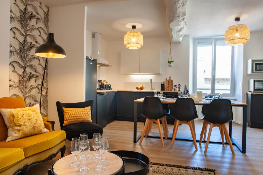 a living room with a yellow couch and a table and chairs at Duplex contemporain dans maison du XVIIème siècle in Fougères