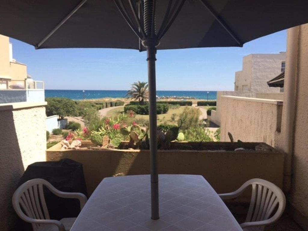 une table et des chaises avec un parasol sur un balcon dans l'établissement Bel appartement 3 pièces - 6 pers - Accès plage direct - Parking - TV/Lave-vaisselle/Lave-linge - FR-1-81-273, au Barcarès