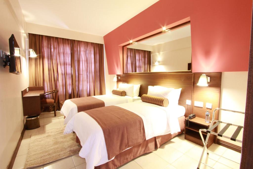 a hotel room with two beds and a mirror at Hotel Rio in Nairobi