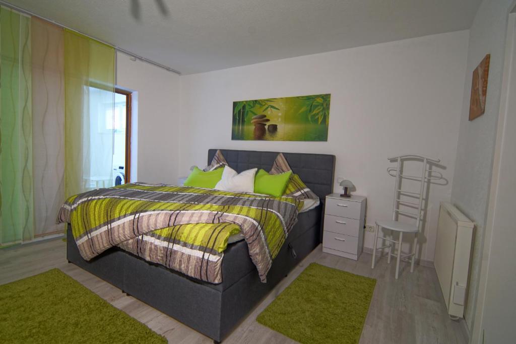 a bedroom with a bed with green pillows and a chair at Kleines Glück in Burgbrohl