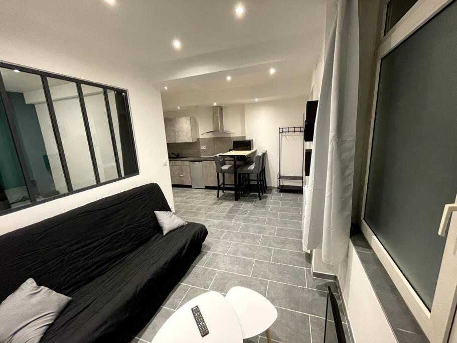 a bedroom with a black bed and a kitchen at Jolie T2 au coeur des collines in Les Veyrières