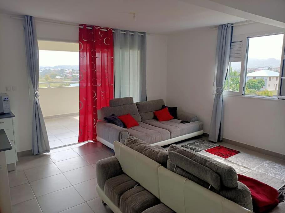 a living room with a couch and red curtains at À 10min de la plage, agréable appartement lumineux in Le Robert