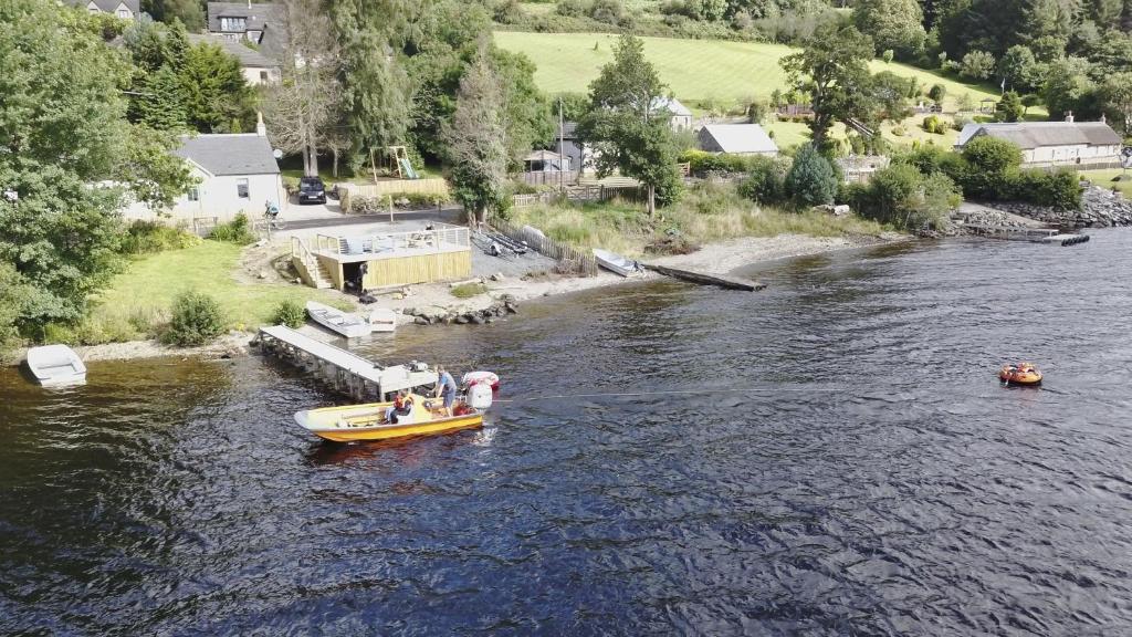 a yellow boat in a river with people on it at Earnbank in Lochearnhead