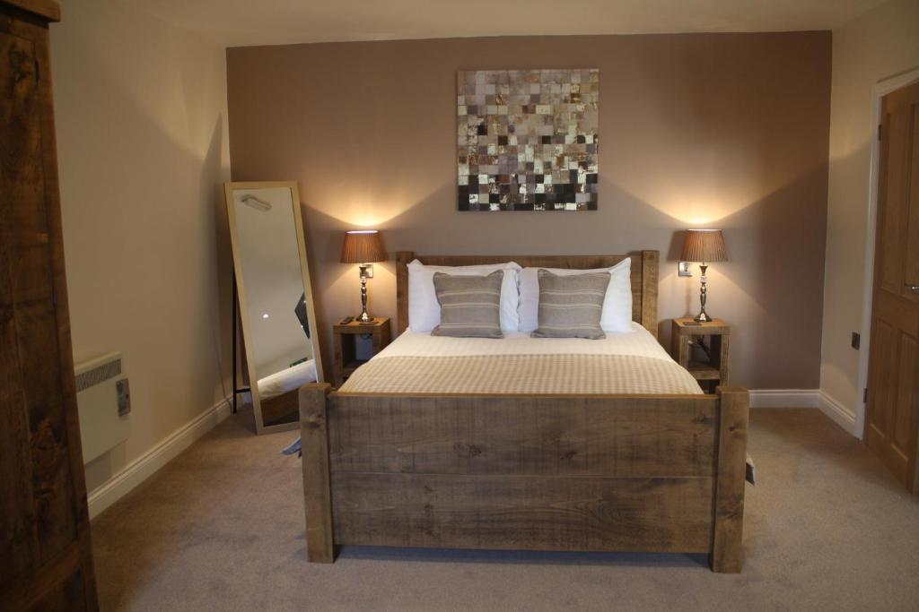 um quarto com uma cama, 2 candeeiros e um espelho em The Woodman Inn em Bedale