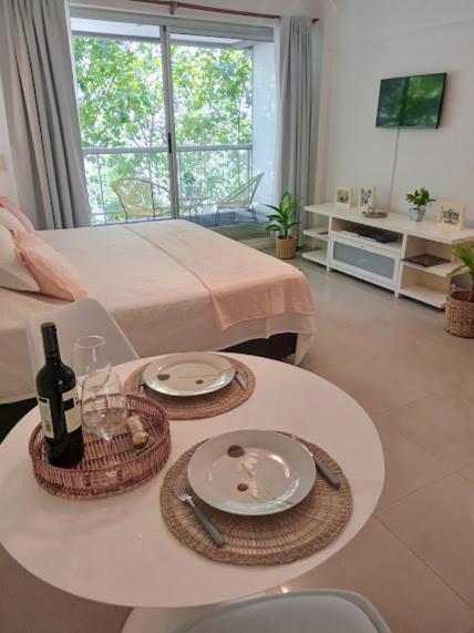 Habitación con cama y mesa con platos y botellas de vino. en Be Happy Studio Palermo Soho en Buenos Aires
