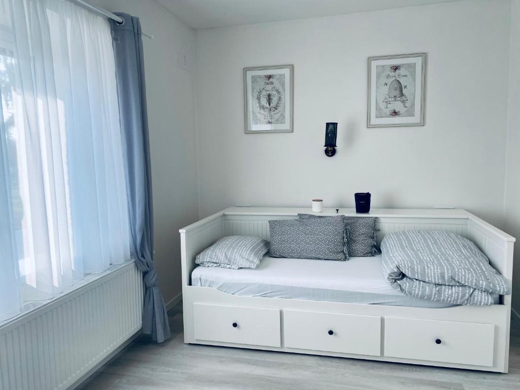 een wit bed in een witte kamer met een raam bij Apartmán U včelína in Chlumec nad Cidlinou