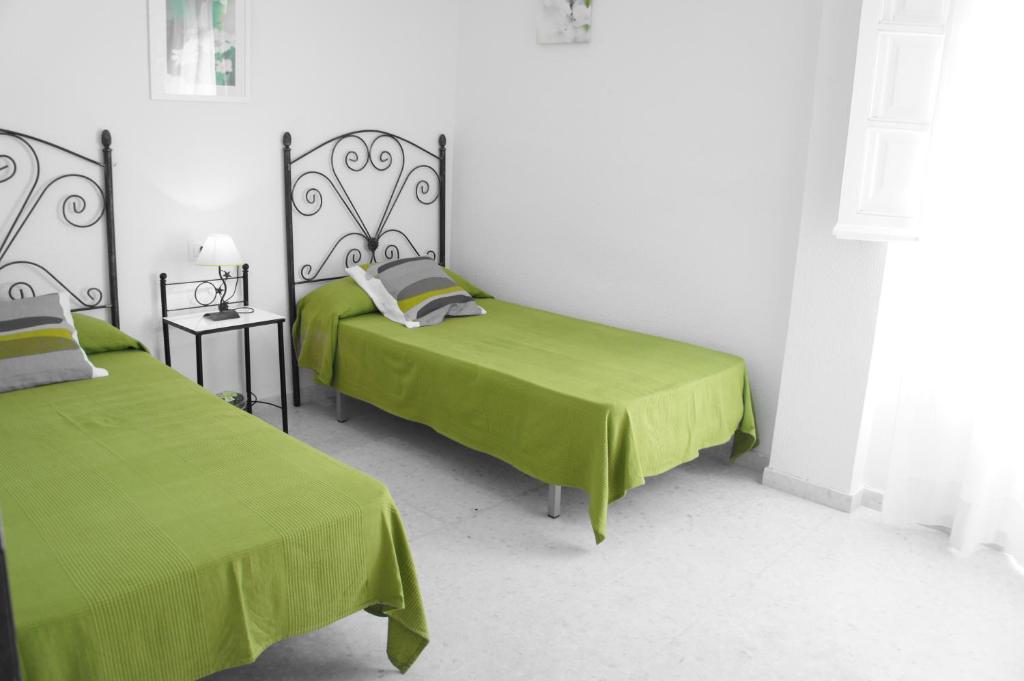 2 camas en una habitación blanca con sábanas verdes en Apartamento Casa de la Parra, en Vejer de la Frontera