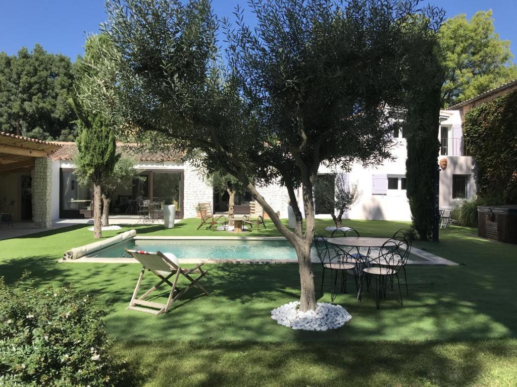 a garden with a table and chairs and a tree at La Maison 1440 in LʼIsle-sur-la-Sorgue