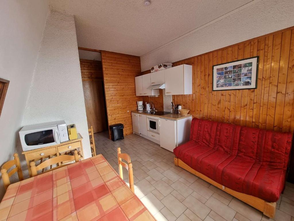 a living room with a red couch and a kitchen at Appartement Saint-Michel-de-Chaillol, 2 pièces, 5 personnes - FR-1-393-6 in Saint-Michel-de-Chaillol