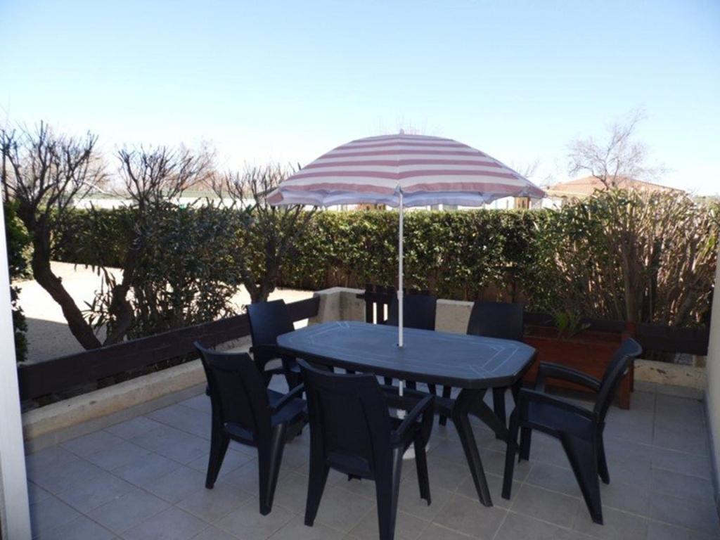 une table et des chaises bleues avec un parasol dans l'établissement Appartement T2 cabine en RDC avec terrasse privative, parking et équipements confortables. - FR-1-326-383, à Marseillan