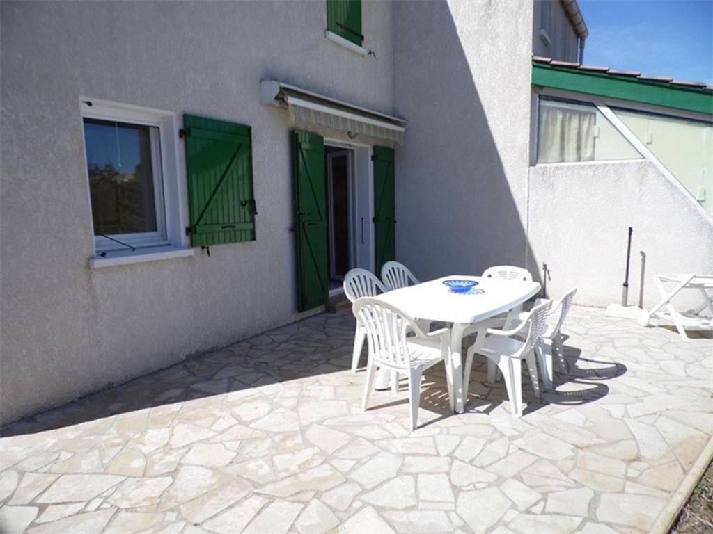 un patio avec une table et des chaises et un bâtiment dans l'établissement Maison mitoyenne duplex avec terrasse, garage et parking, proche plage, équipée pour 4 à 6 personnes - FR-1-326-385, à Marseillan