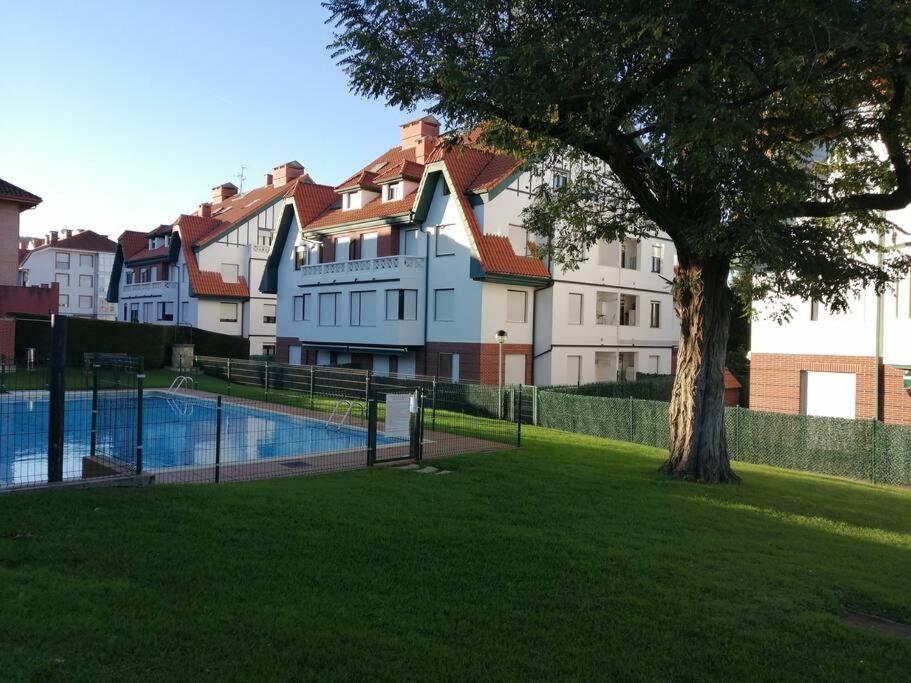 a building with a tree and a swimming pool at APARTAMENTO LA GRANJA EN GAMA(next to Santoña) in Gama