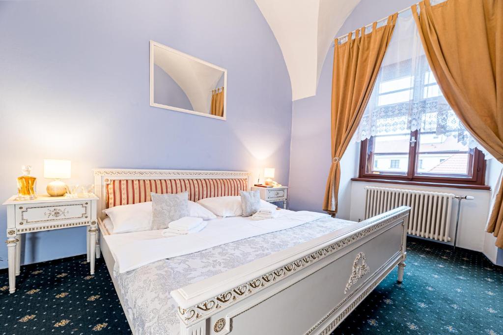 a white bedroom with a bed and a window at Nové Adalbertinum in Hradec Králové