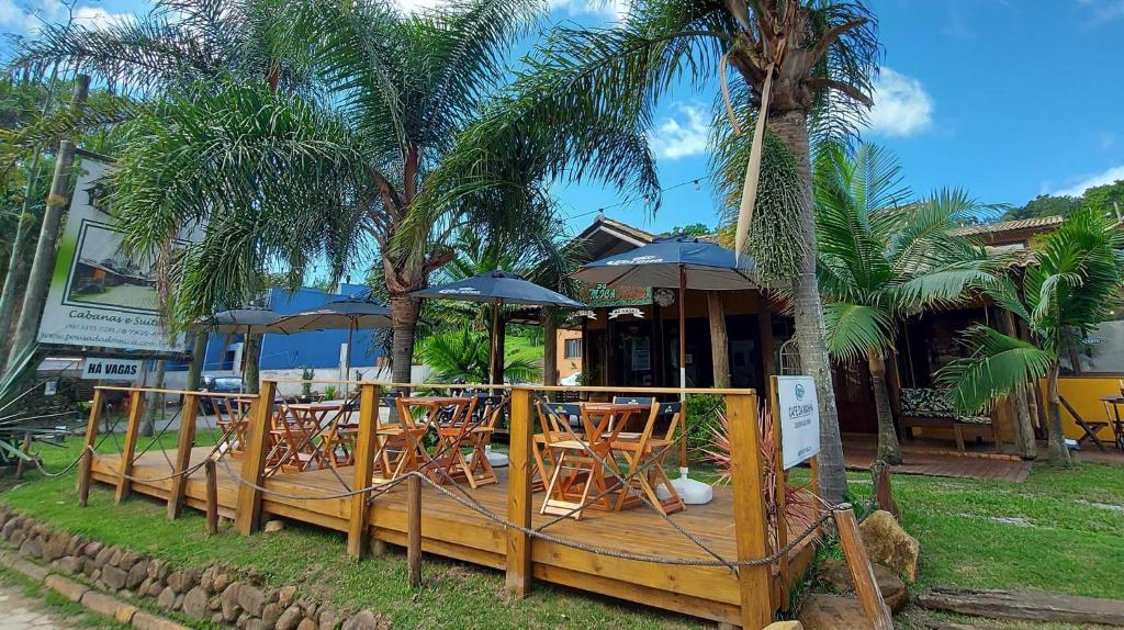 a deck with chairs and umbrellas in front of a restaurant at Pousada do Mica in Praia do Rosa