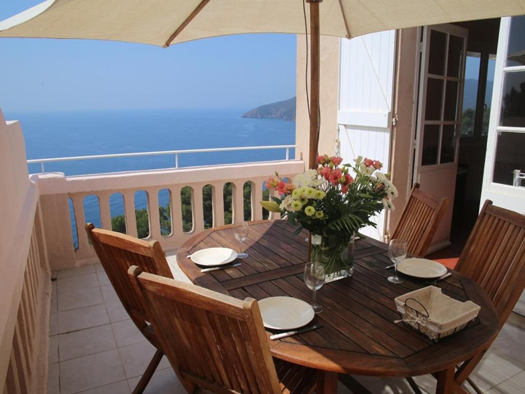 une table en bois avec un vase de fleurs sur le balcon dans l'établissement Appartement T3 75m², 2 terrasses avec accès direct aux calanques, WIFI, parking privatif - FR-1-100-147, à Cavalaire-sur-Mer