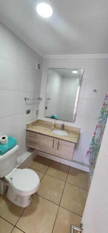 a bathroom with a toilet and a sink and a mirror at Departamento Iquique Nuevo Centro in Iquique