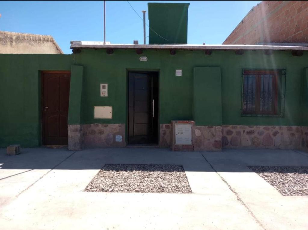 un edificio verde con dos puertas laterales en Cabaña la Encantada en Humahuaca
