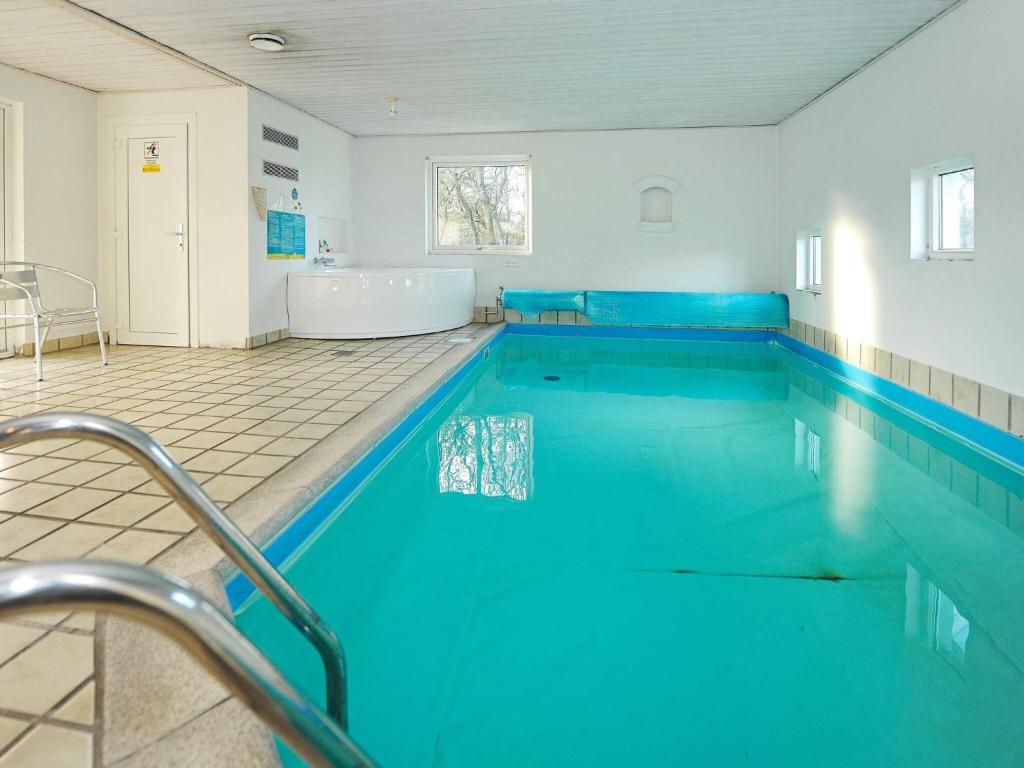 een groot zwembad met blauw water in een badkamer bij Holiday Home Hedevang V in Oksbøl